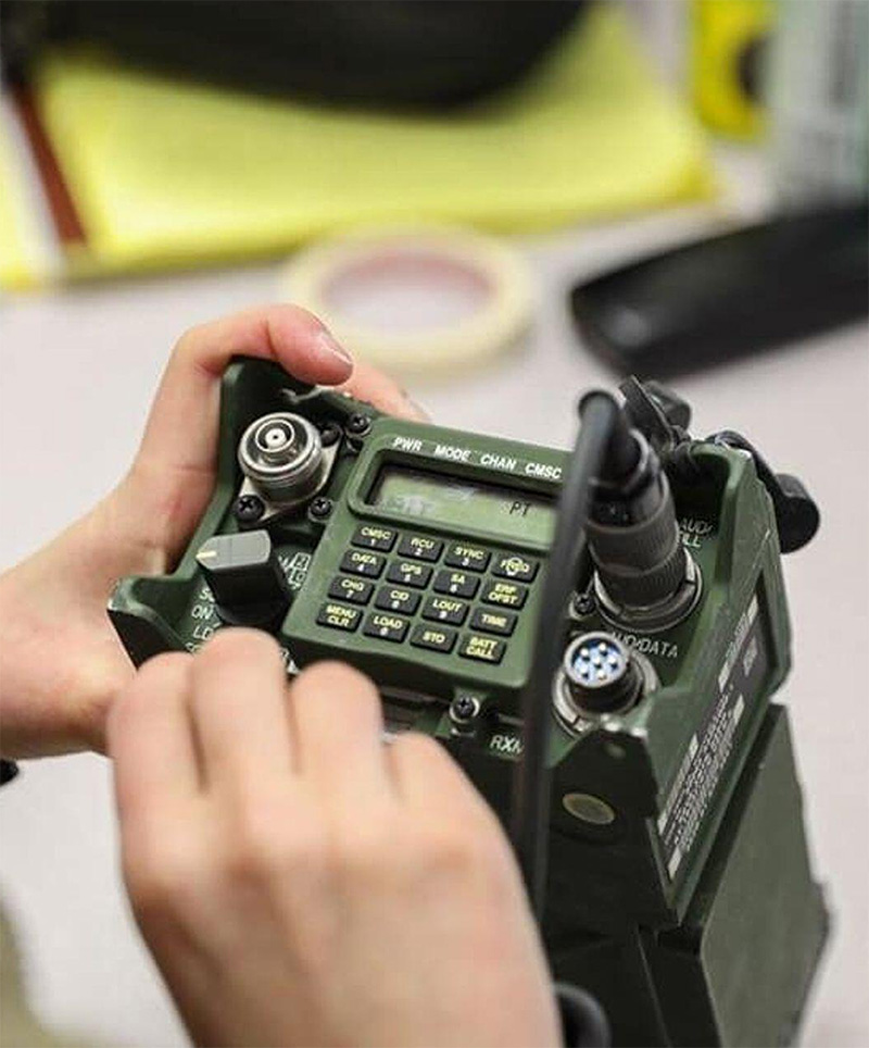 A soldier’s hands operating a rugged radio equipped with a Grayhill 51 Series Rotary Switch and custom sealed keypad.