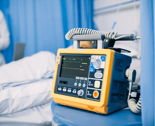 A yellow and blue patient monitor sits in a hospital room.