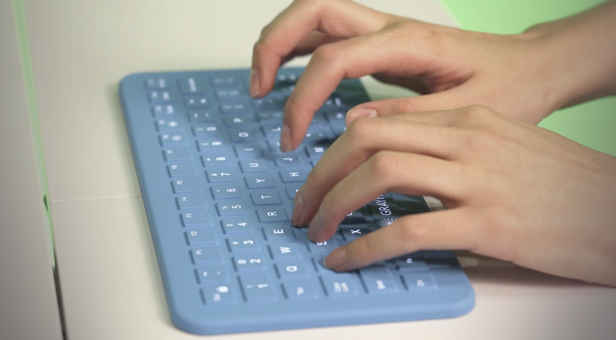 Woman's hands typing on a blue Grayhill CliniKey medical keyboard.